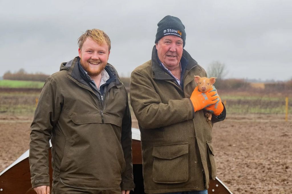 Kaleb Cooper and Jeremy Clarkson holding a piglet in their Cotswolds garm