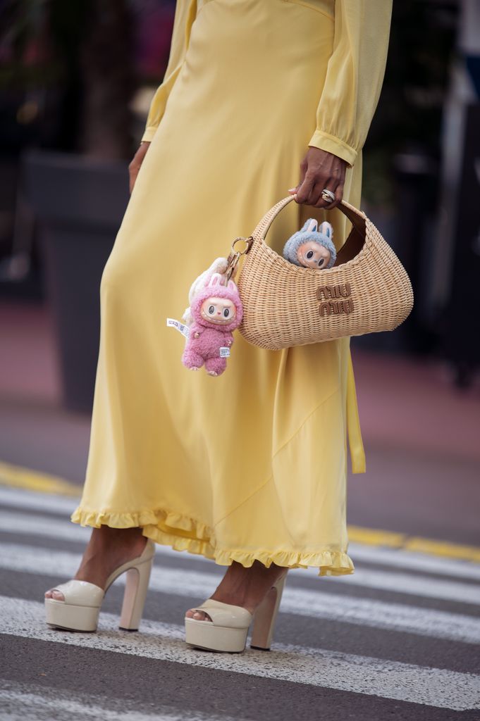 ufi Alexander wears an all Miu Miu look made of butter yellow long summer dress, off white pumps high heels with platform and straw Miu Miu bag with attached Labubu bag charms during day five of the 78th Cannes Film Festival on May 17, 2025 in Cannes, France.