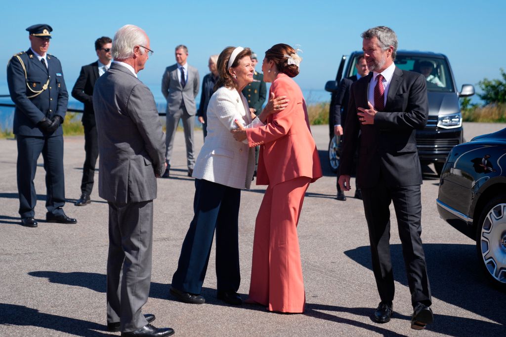 Queen Mary of Denmark (C-R) and Queen Silvia of Sweden (C-L) hug