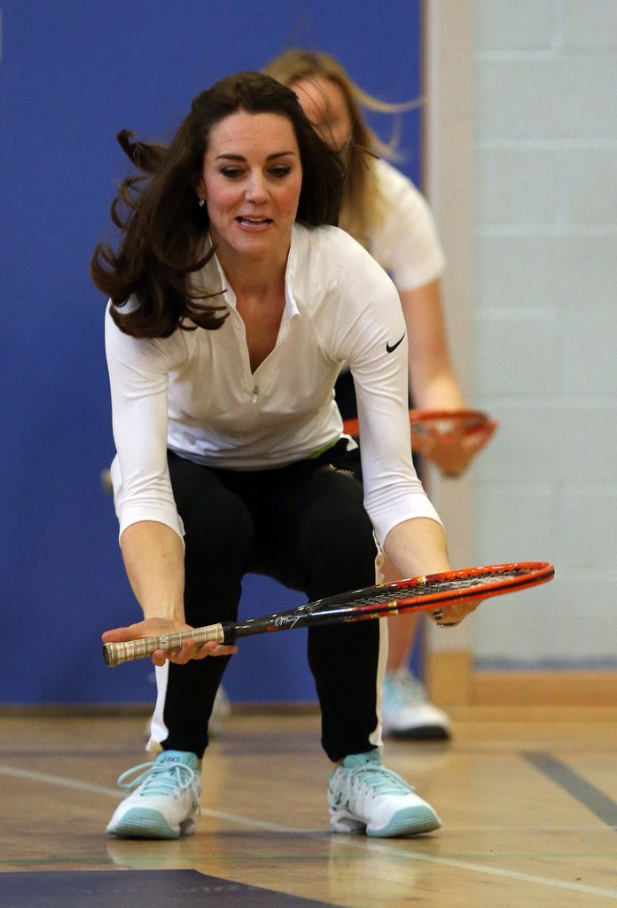 Kate squatting holding tennis racket