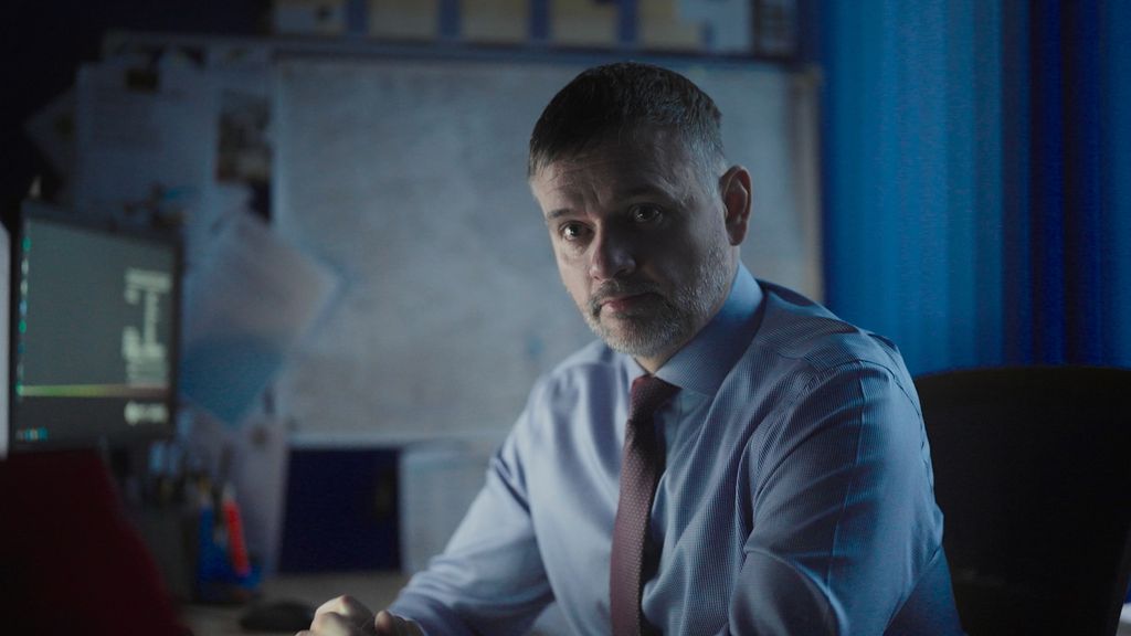 man in blue shirt sitting in dimly lit office