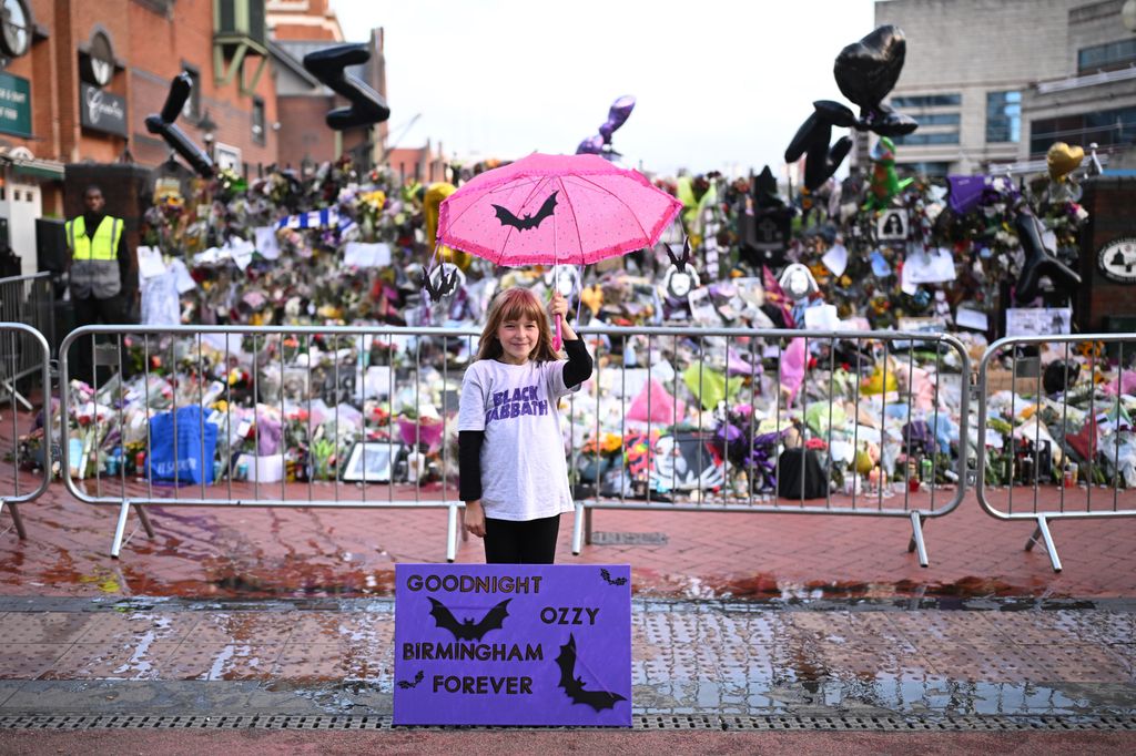 BIRMINGHAM, ENGLAND - JULY 30: Eliza Finn-OâShea of Birmingham poses in front of tributes prior Ozzy Osbourne's funeral cortege is set to travel through his home city of Birmingham on July 30, 2025 in Birmingham, England. The Black Sabbath frontman passed away on July 22nd at the age of 76. His death occurred just a little over two weeks after his final live performance at the 'Back to the Beginning' concert in his hometown of Birmingham. (Photo by Leon Neal/Getty Images)