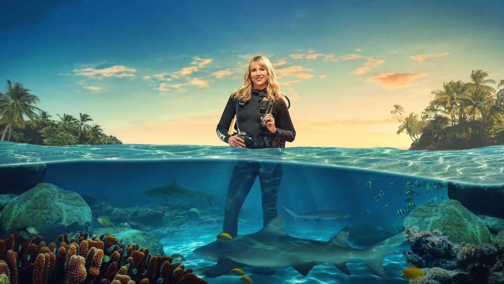 woman wearing diving gear standing in water with sharks