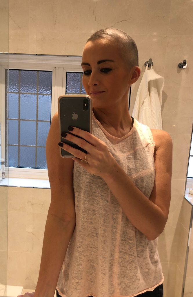 woman taking a mirror selfie with a shaved head due to cancer