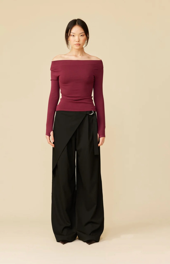 A model poses in a pair of black trousers and a red top