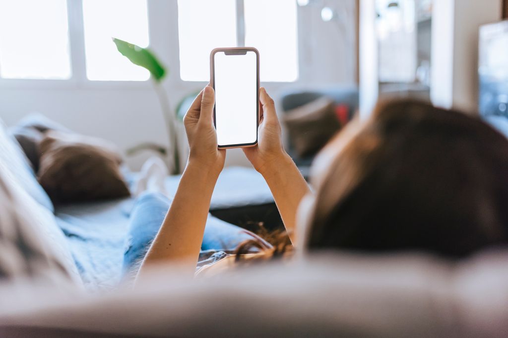 woman sitting on the sofa at home watching the mobile phone