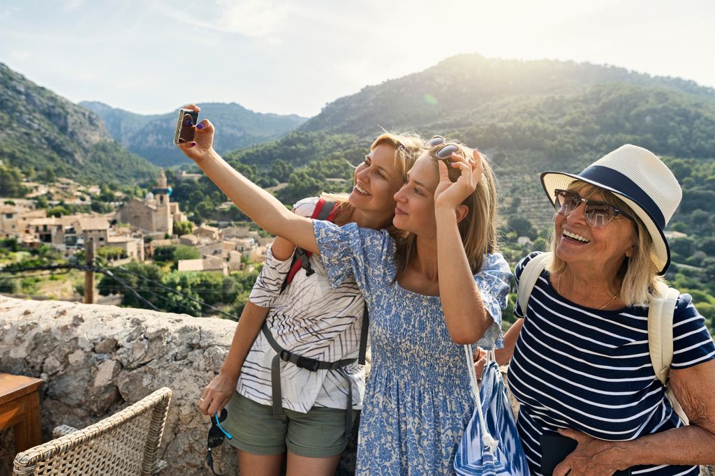 Multi generation family sightseeing beautiful town of Valldemossa. Sunny summer day in Majorca, Spain.
Teenage girl, mother and grandmother are taking selfies. 