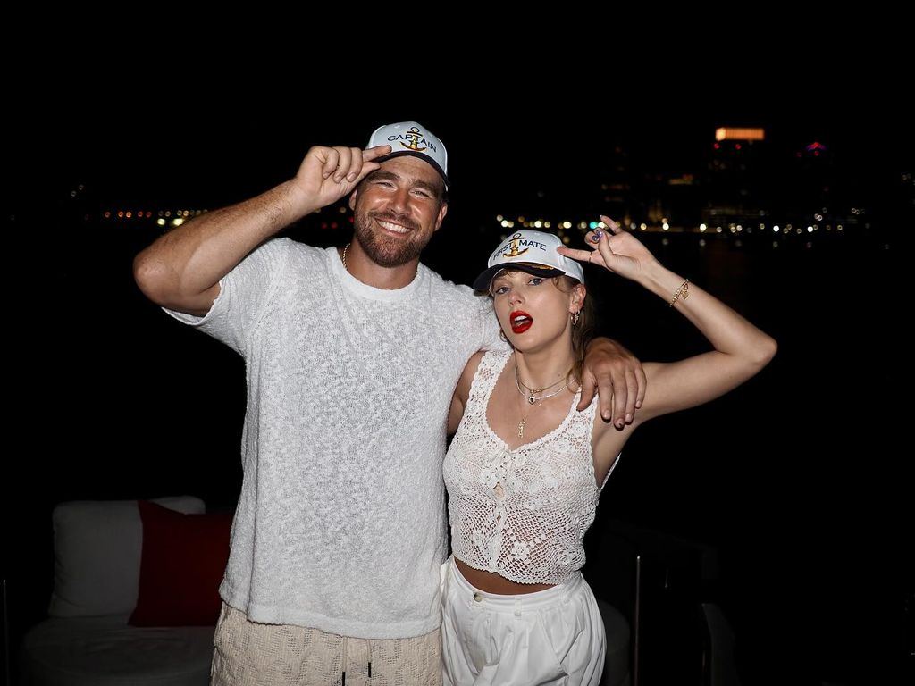 travis kelce and taylor swift holding onto caps on their heads