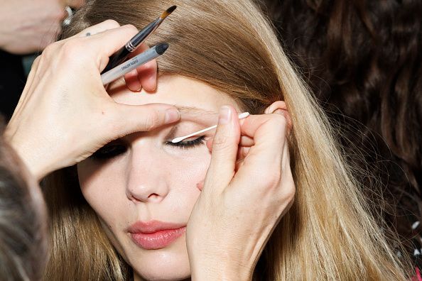 A makeup artist using a Q-Tip on a models eyes to perfect her eyeliner 