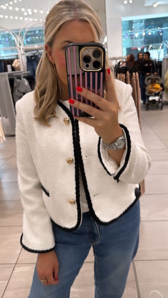Shopping expert Leanne Bayley wearing a white boucle jacket from H&M that has a black trim and gold button. She's styling it with jeans and a white tee. 