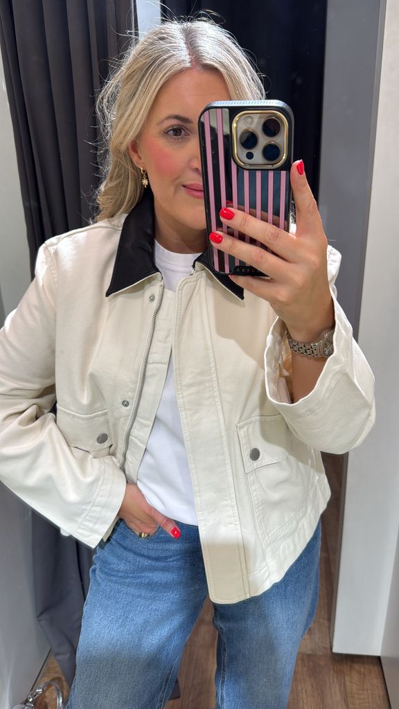Leanne Bayley wearing a cropped barn jacket in the fitting room at Mango. She has styled it with jeans and a white t-shirt
