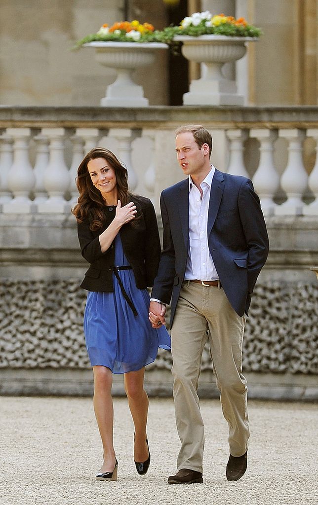 Prince William and his new bride Catherine in black and blue outfit walk hand in hand 