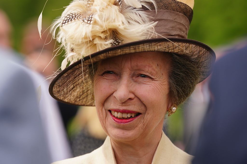 Smiling Princess Anne wearing a yellow hat