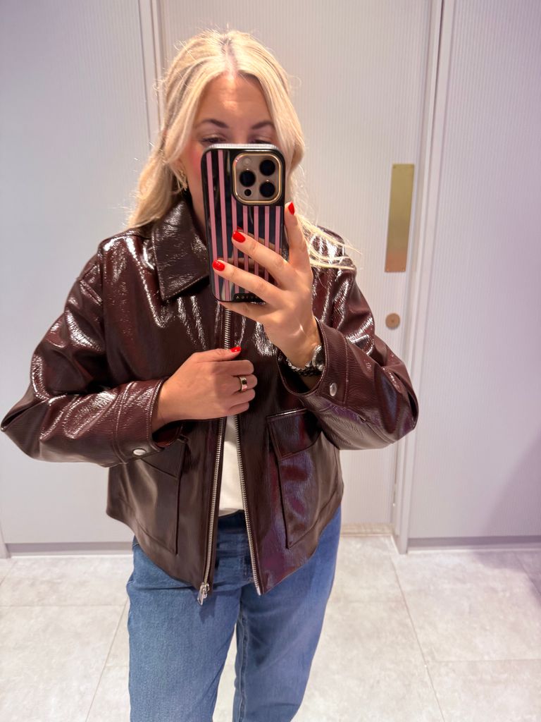 Shopping expert Leanne Bayley wearing a patent cropped jacket in burgundy from Marks & Spencer. She is styling it with blue jeans and a white t-shirt.