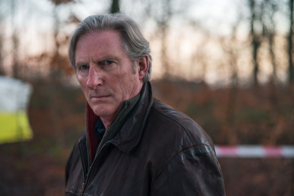 CLOSE-UP OF MAN IN LEATHER JACKET IN WOODS