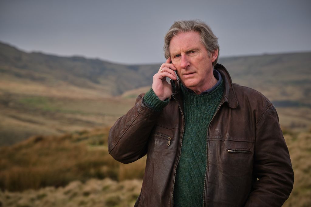 man wearing leather jacket speaking on phone on moors