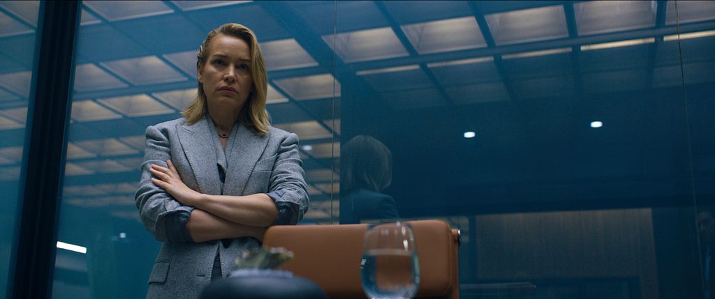woman in grey suit folding arms in interview room