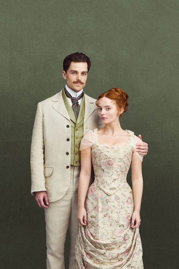 man in suit and woman in period dress against green background