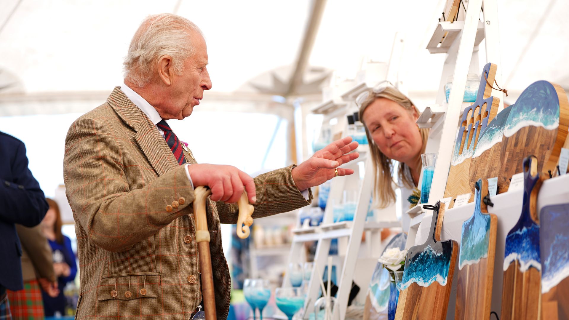 King Charles looking at wooden chopping boards that have a sea design