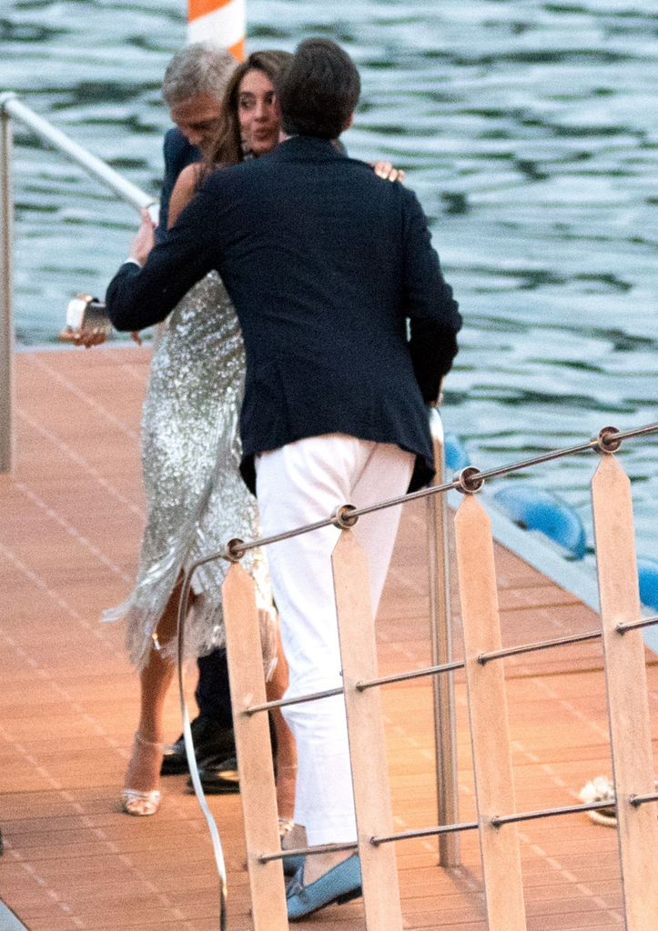 Amal Clooney is greeted by a friend on the dock in Italy
