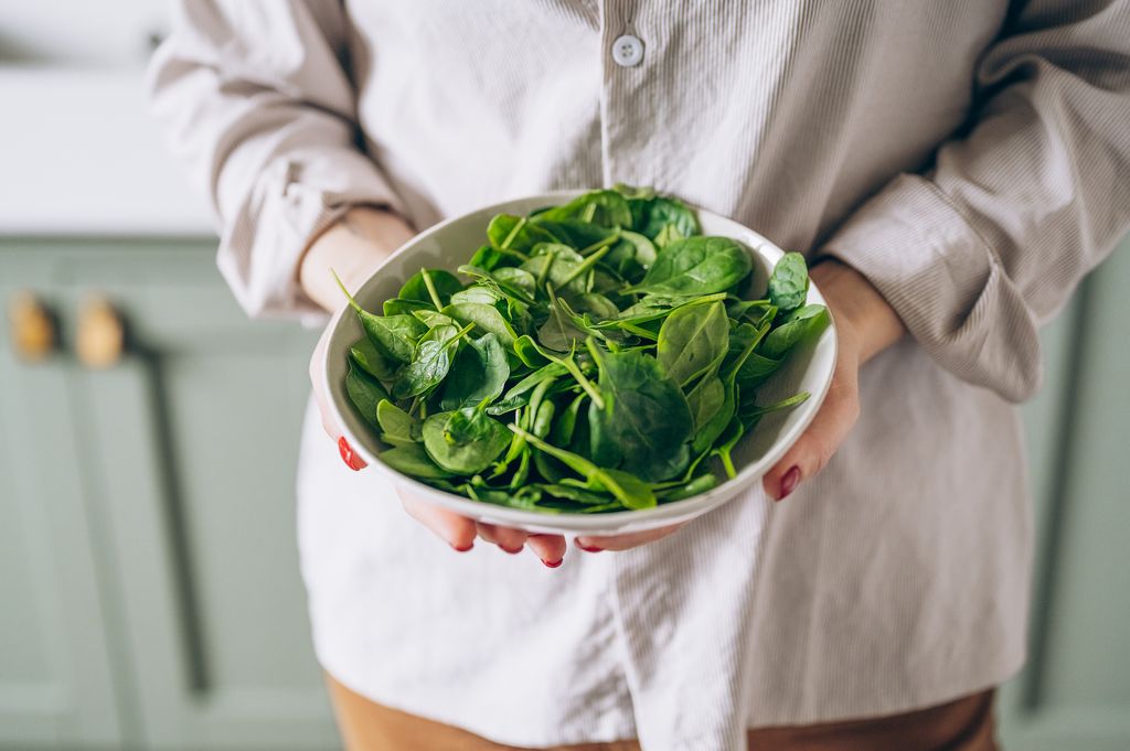Spinach in a bowl held by woman