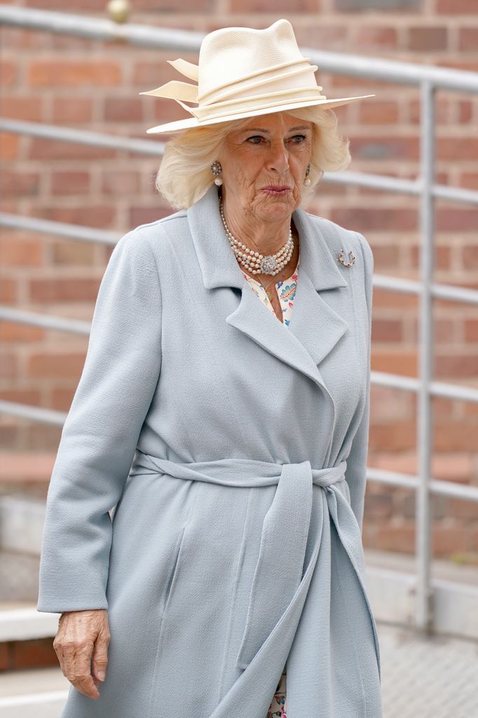 Queen Camilla wearing blue coat, pearls and hat