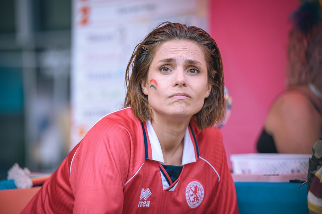 Woman in football shirt with rainbow painted on face