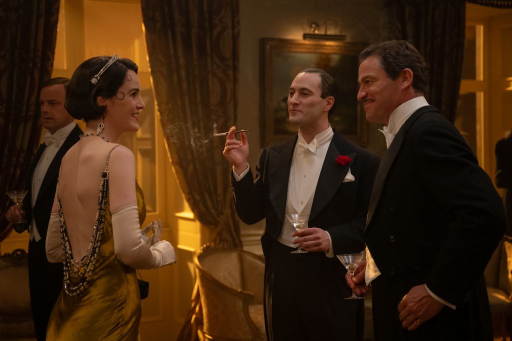 woman in period gown, next to two men in tuxedos