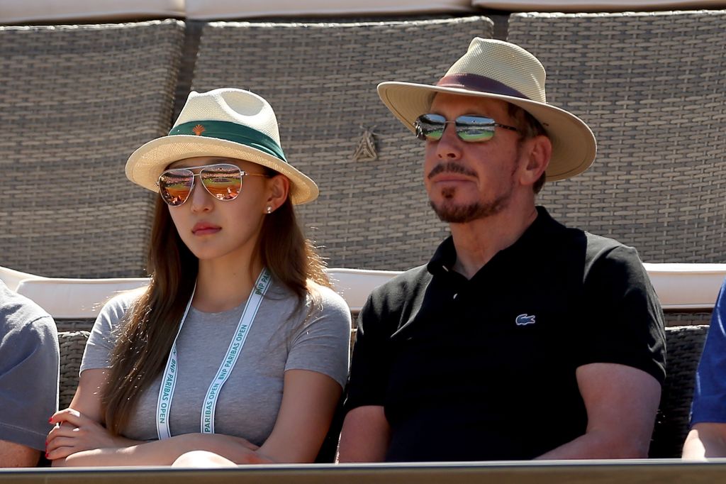 The couple look glum watching sports with hat and sunglasses on