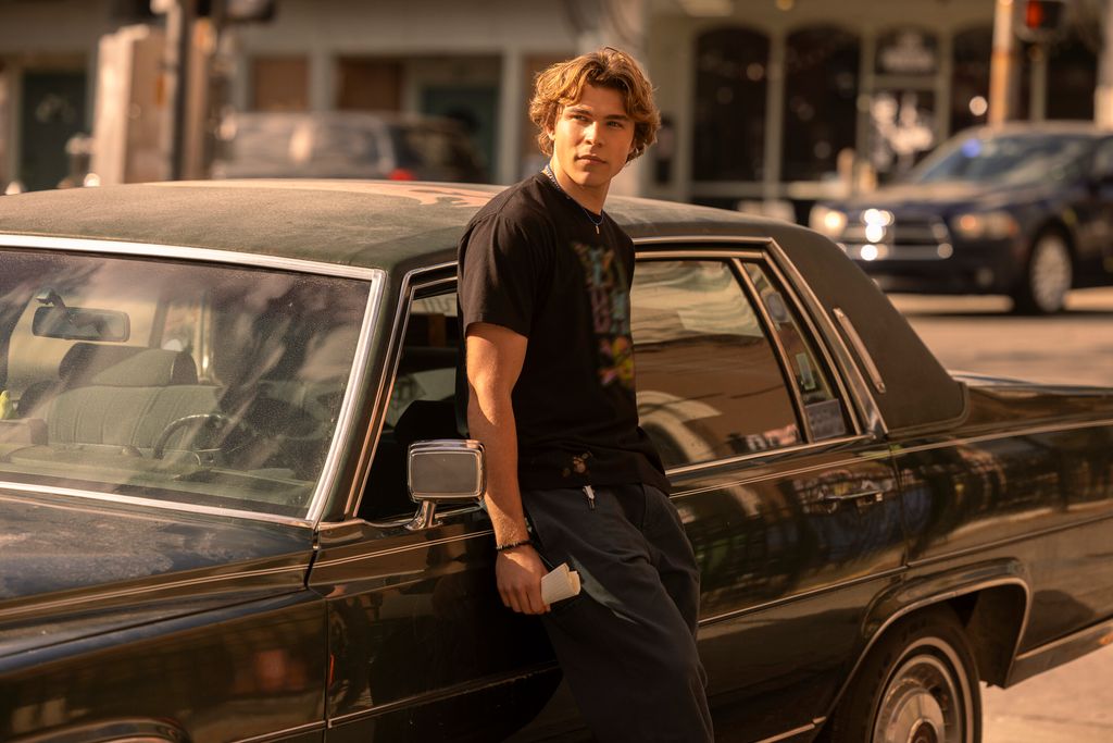 blonde teen boy leaning against classic car