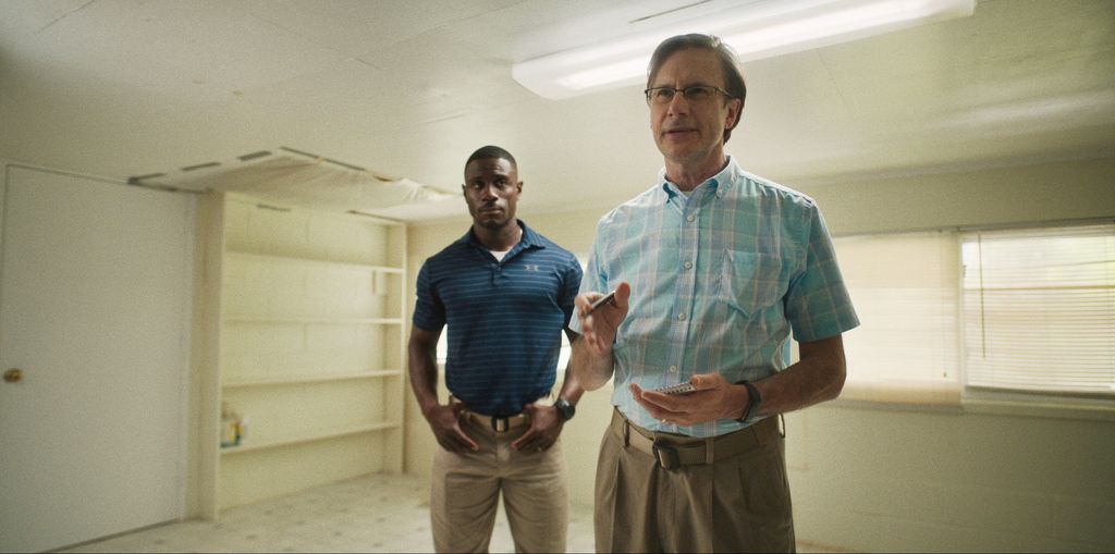 Two men stand in a white room