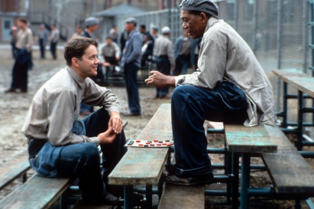 Tim Robbins and Morgan Freeman sitting outside on the benches playing checkers and talking in a scene from the film 'The Shawshank Redemption', 1994. (Photo by Castle Rock Entertainment/Getty Images)