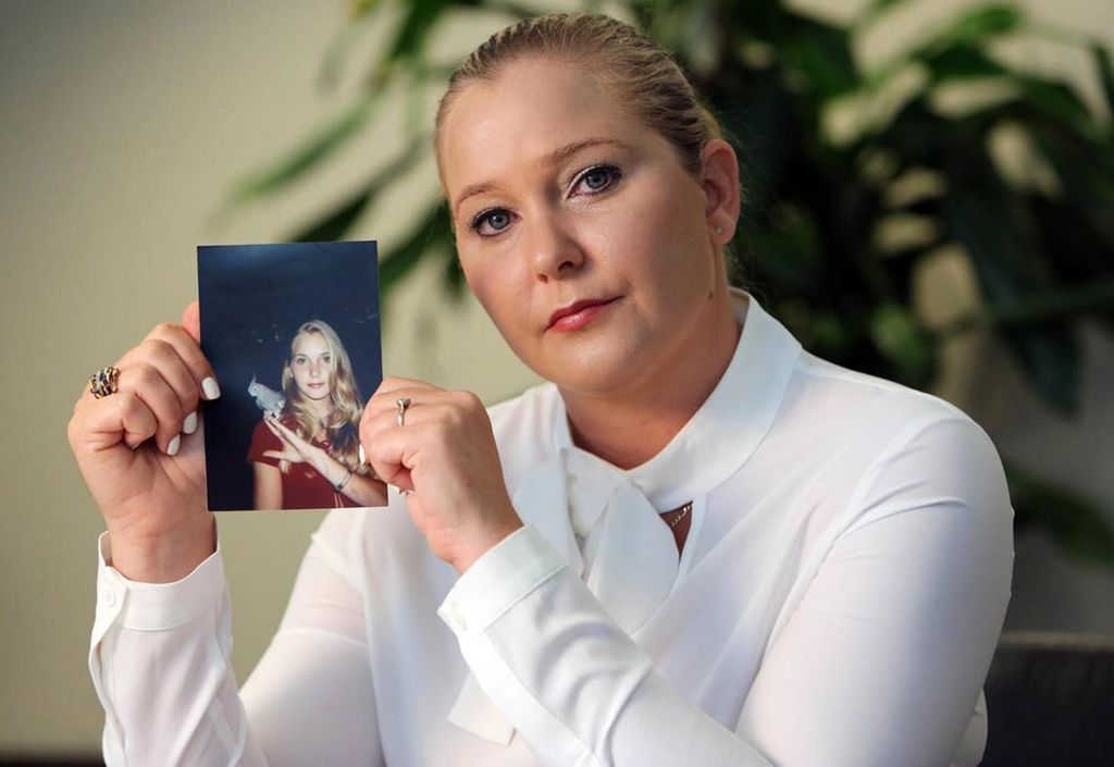 photo of virginia giuffre holding a photo of herself as a teenager