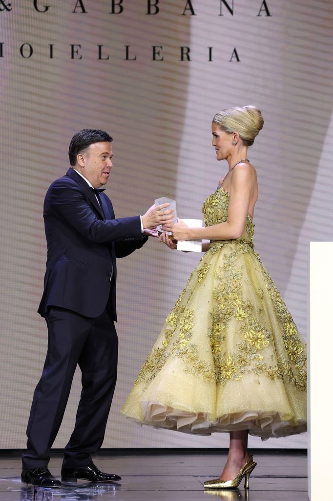 Kitty Spencer being handed award in gold dress