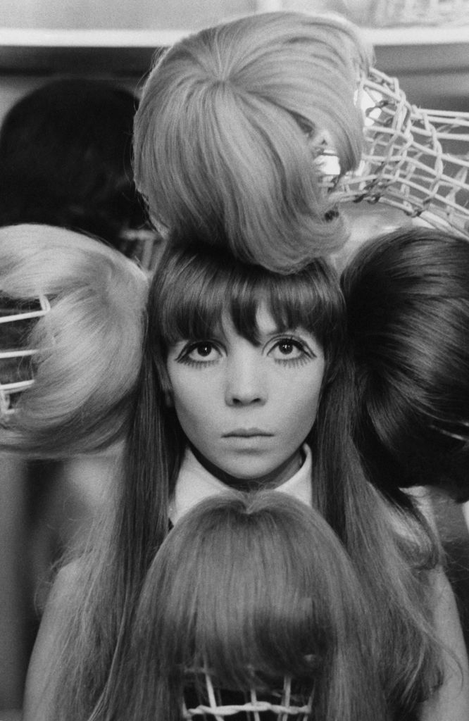 Penelope posing surrounded by wigs