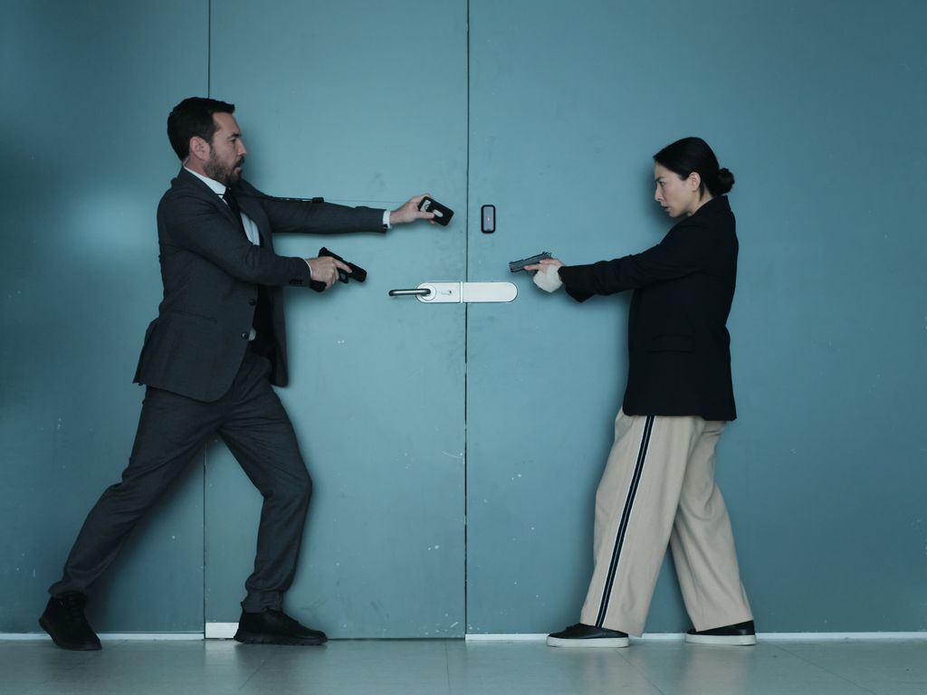 man and woman holding guns outside closed door