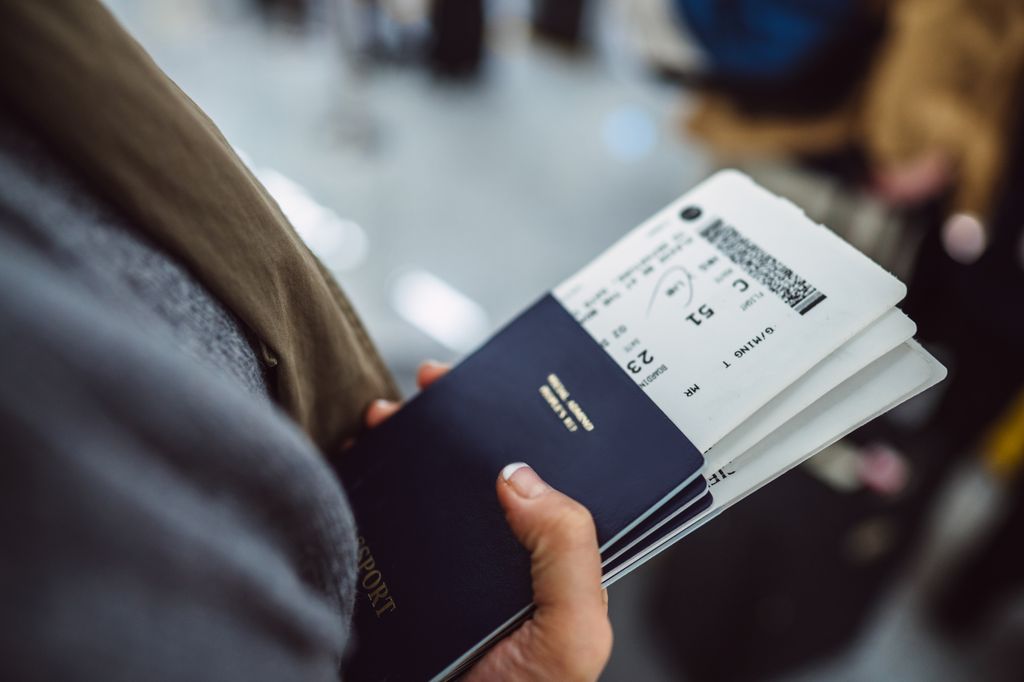 Womanâs hands holding passports & boarding passes of her family while waiting at the check-in counter in the airport.