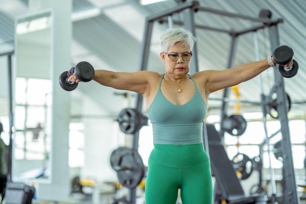  senior woman doing dumbbell flyes exercise in the gym