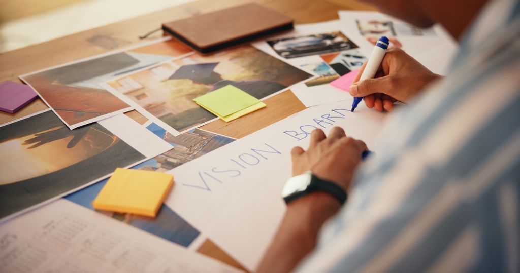 Someone creating a vision board using post it notes and printed images