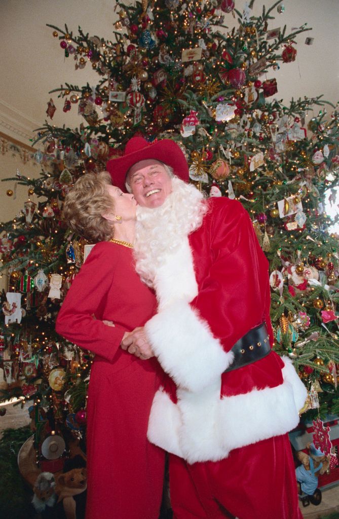 Nancy Reagan launches the Christmas season at the White house 12/9 with a kiss for Santa Claus, also known as Larry Hagman, who stars in the role of J. R. Ewing in TV's Dallas, 1985