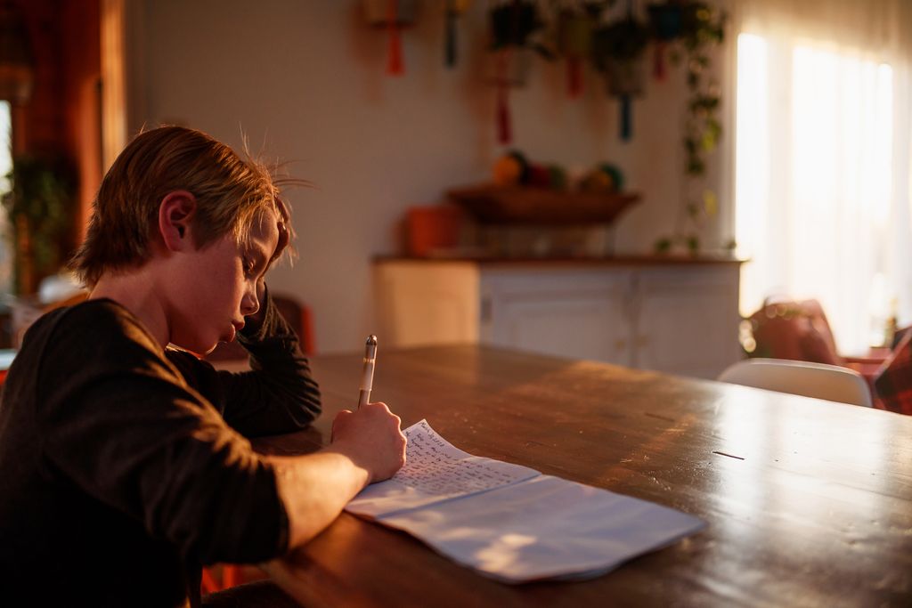 boy writing in a journal at sunset 