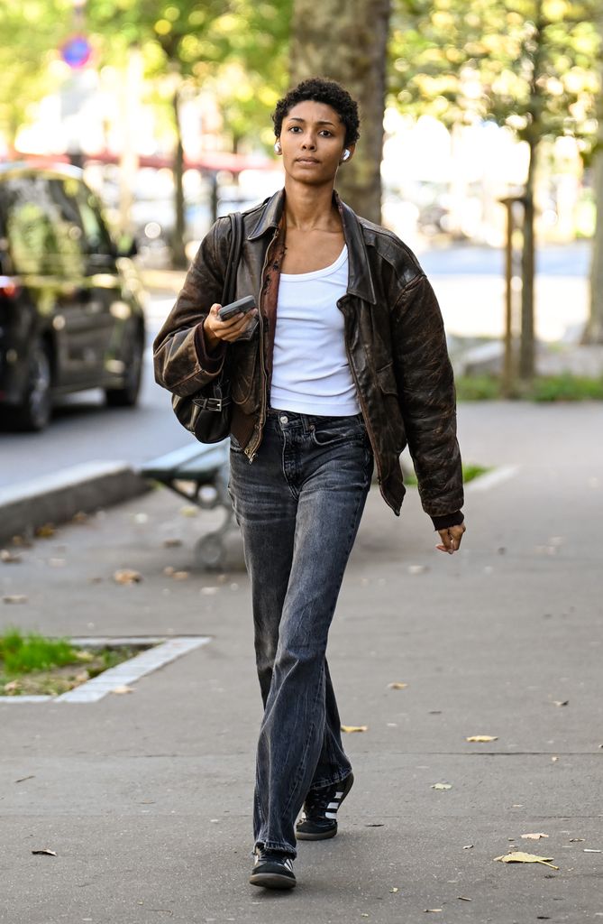 A model is seen wearing a brown jacket, white shirt, charcoal jeans and black and white Adidas sneakers outside the Dries Van Noten show during the Womenswear spring/summer 2026 as part of Paris Fashion Week 