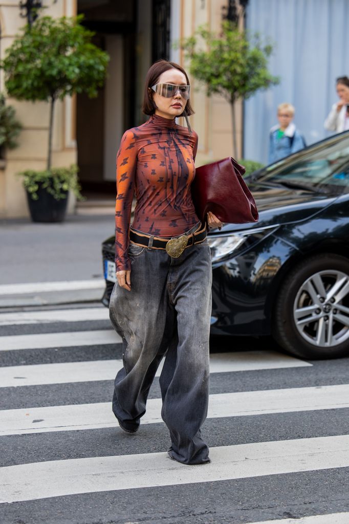 A guest wears long shirt, denim jeans, burgundy bag outside Acne during the Womenswear spring/summer 2026 as part of Paris Fashion Week 