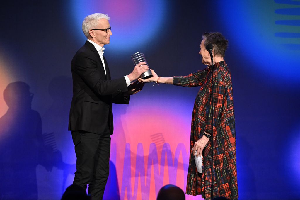 Anderson Cooper receiving a Webby award from Laurie Anderson on stage in May 2023