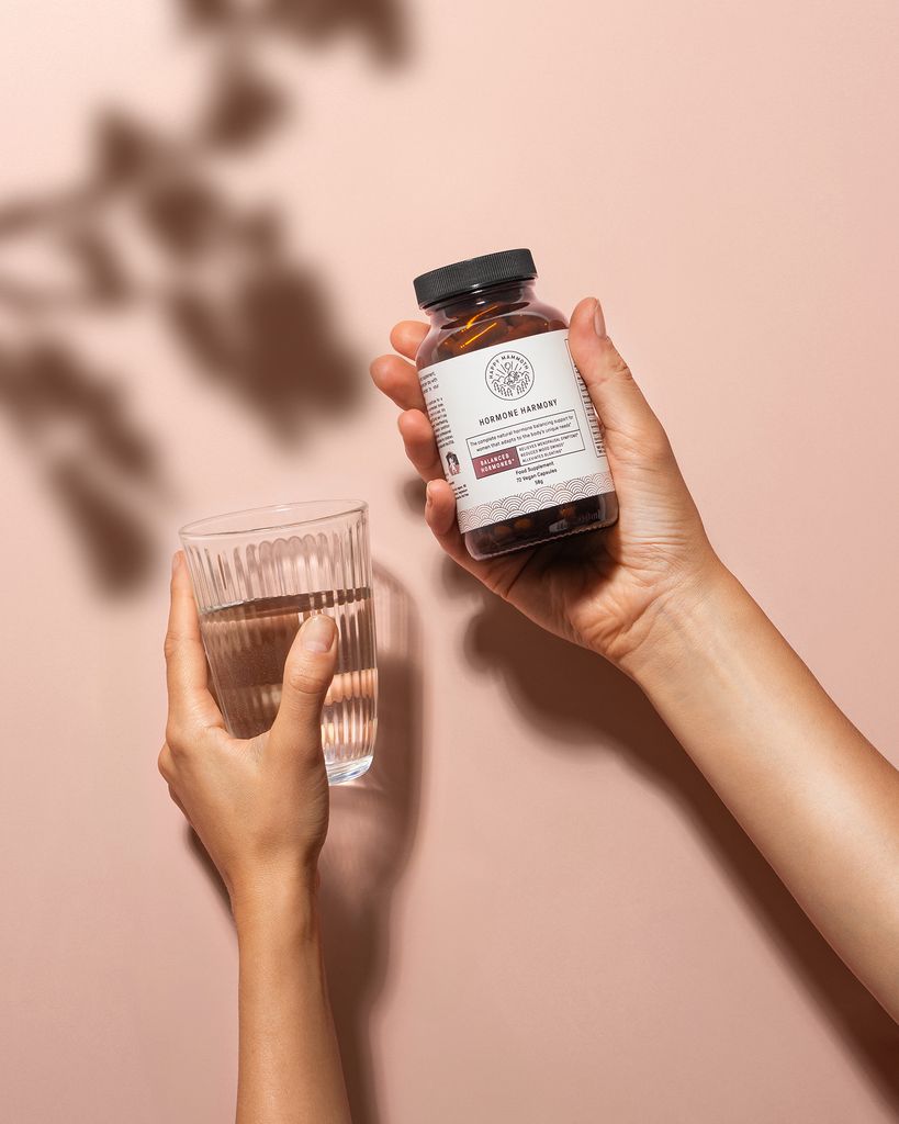 hand holding supplements and glass of water