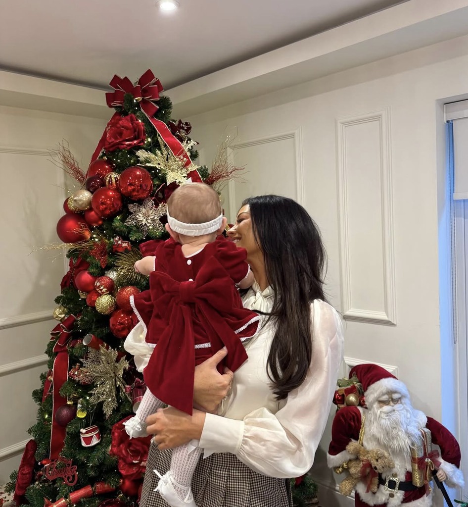 Jess Wright holding her baby niece, Palma, by Christmas tree
