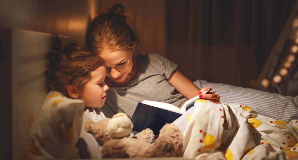 woman and daughter reading in bed 