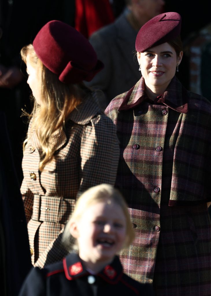 Princess Beatrice and Princess Eugenie outside church on Christmas Day, both wearing oxblood coloured hats and checked coats