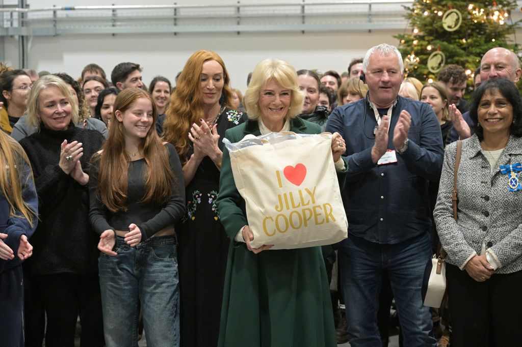 Queen Camilla holds a tote bag with the name of Jilly Cooper on it 