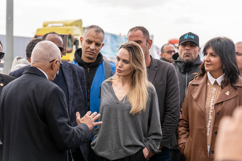 Angelina Jolie in gray jumper speaking to aid workers
